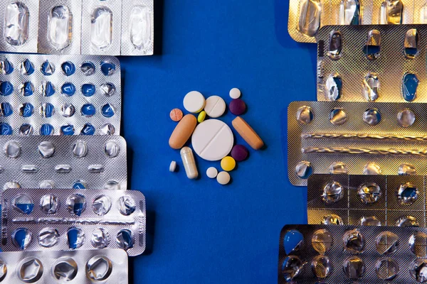Prázdné použité blistr balení a různé pilulky na modrém pozadí — Stock fotografie