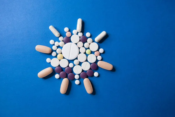 Covid-19 korona virus lék. Barevné lékařské pilulky na modrém pozadí pro léčbu nemocí ncov-19. — Stock fotografie