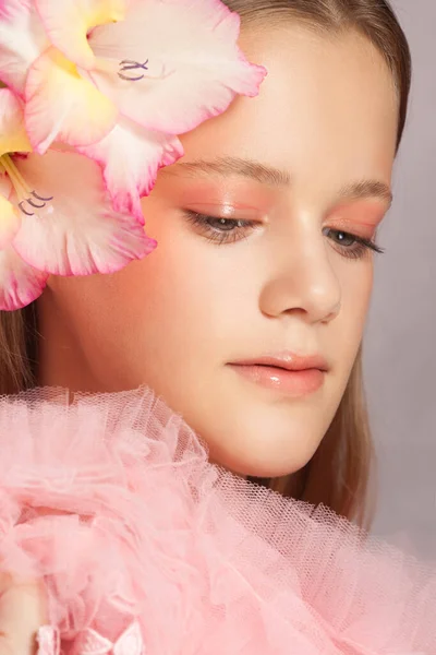 Молодая красивая женщина с идеальной кожей и цветок в волосах на розовом фоне — стоковое фото