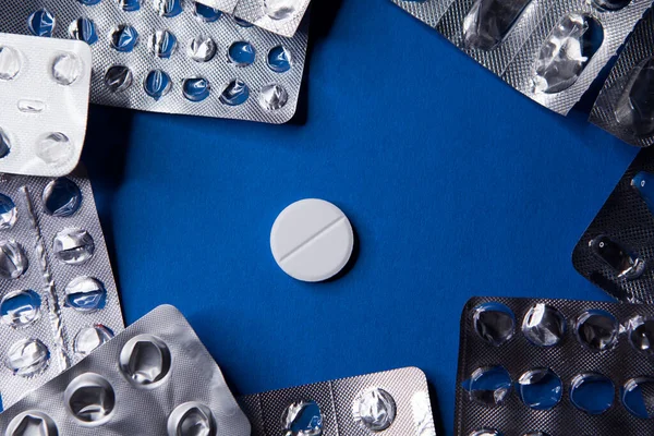 Pacchetto blister vuoto usato e pillola su sfondo blu — Foto Stock