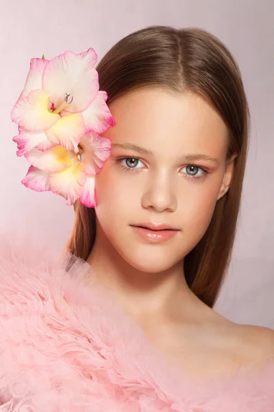 Young beautiful woman with perfect skin and a flower in her hair on pink background — Stock Photo, Image