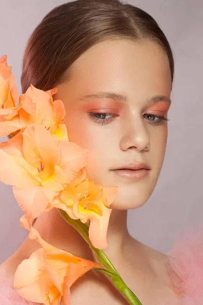 Jonge mooie vrouw met perfecte huid en een bloem op roze achtergrond — Stockfoto