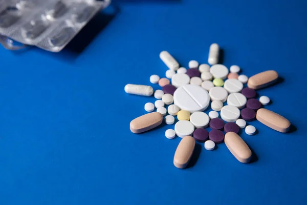 Лекарство от короны Ковид-19. Красочные медицинские таблетки на синем фоне для лечения заболеваний ncov-19. — стоковое фото