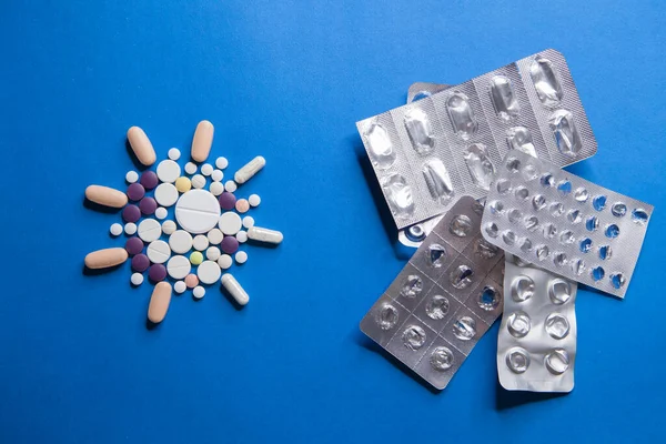 Cura del virus Covid-19 corona. Pillole mediche colorate su sfondo blu per il trattamento delle malattie ncov-19. — Foto Stock