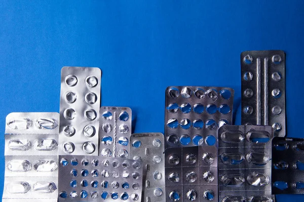 Empty blister packs of pills in the form city on blue background. — Stock Photo, Image