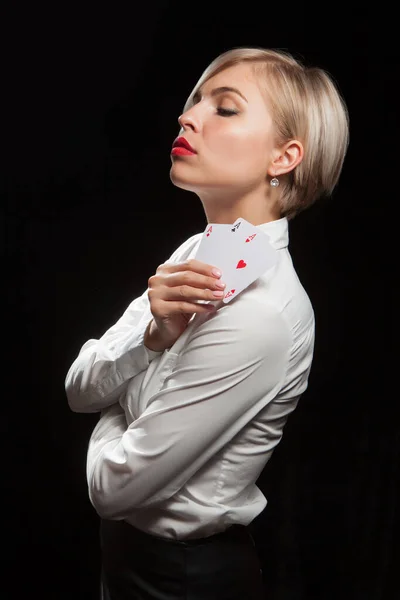 Schöne blonde Frau zeigt eine Pokerkarte auf schwarzem Hintergrund — Stockfoto