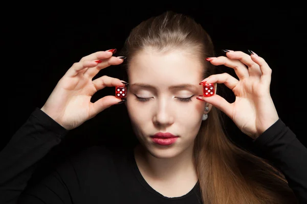 Mulher bonita com olhos fechados segurando um dados vermelhos em um fundo preto — Fotografia de Stock