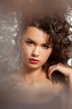 Yüzünde altın kar taneleri ve dalgalı saç stiliyle yaratıcı kış makyajı.