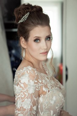 Gelin makyajı saç stili. Beyaz elbiseli muhteşem genç bayan evde..