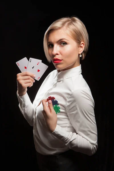 Hermosa mujer rubia mostrando cartas de póquer y fichas de juego sobre fondo negro — Foto de Stock