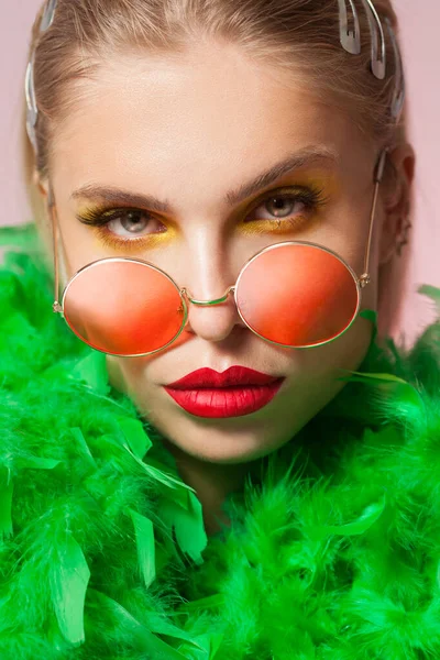 Blonda unga kvinnor bär runda ram solglasess och grön fjäder boa — Stockfoto