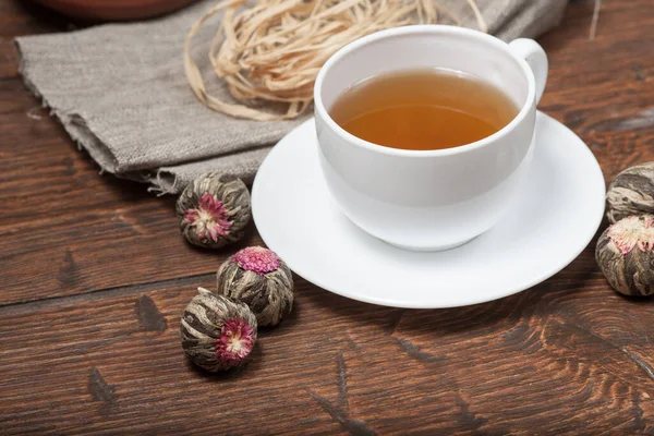 Šálek čaje s kyticí čínského čaje na starém dřevěném stole — Stock fotografie