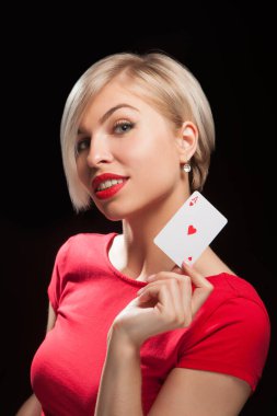 Güzel sarışın kadın siyah arka planda poker kartı gösteriyor.