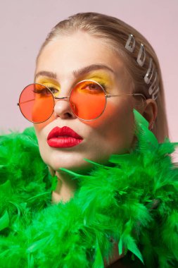 Blonde young women wearing round frame sunglasess and green feather boa clipart