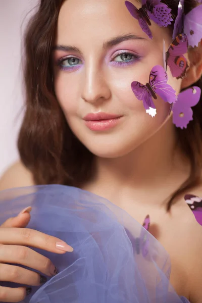 Mooie jonge vrouw met kunstmatige vlinder in krullend haar. — Stockfoto