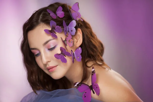 Hermosa joven con mariposa artificial en el pelo rizado. —  Fotos de Stock