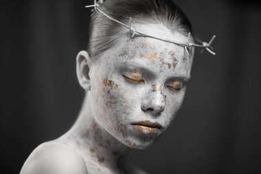 Dikenli tel bir çelenk içinde mermer ciltli genç bir kadının portresi..