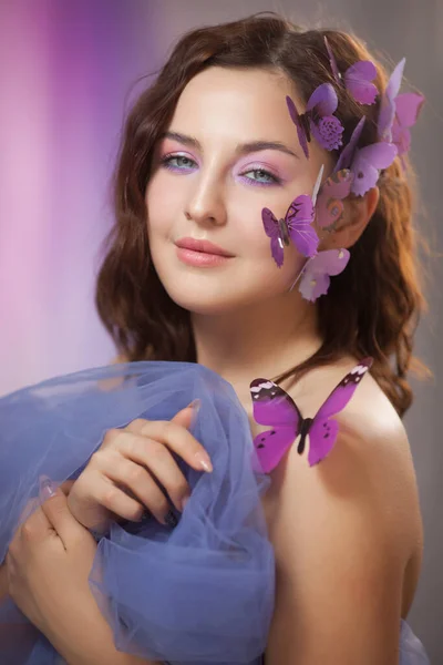 Mooie jonge vrouw met kunstmatige vlinder in krullend haar. — Stockfoto