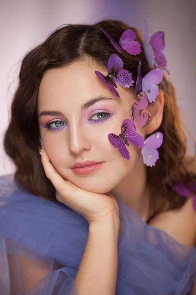 Piękna młoda kobieta ze sztucznym motylem w kręconych włosach. — Zdjęcie stockowe