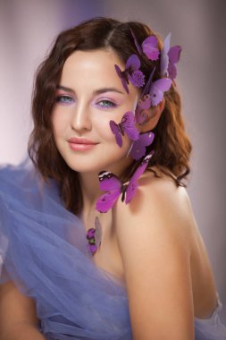 Kıvırcık saçlı, yapay mor kelebekli güzel bir genç kadın..
