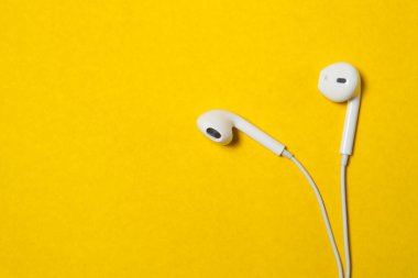 Beyaz kablo kulaklık sarı arkaplanda metin için yer var.