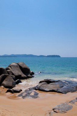 Tayland 'da güneşli bir günde mavi denize karşı kocaman taşları olan kumsal..