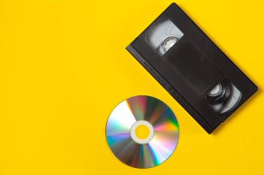 Sarı arka planda video kaset ve CD kaset. Üst Manzara. Anılarını modern medyada sakla. Düz konsept.