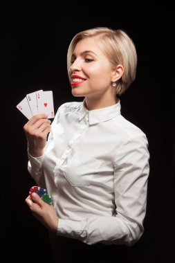 Güzel sarışın kadın siyah arka planda poker kartları ve kumar fişleri gösteriyor.