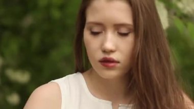 Çiçekli kuş kirazının yanında uzun dalgalı saçlı bir kadın. Bahar geldi. Çiçek açan doğa.