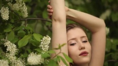 Uzun dalgalı saçlı bir kadın kiraz çiçeğinin yanında rahatlar.