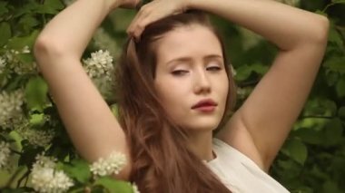 Uzun dalgalı saçlı bir kadın kiraz çiçeğinin yanında rahatlar.