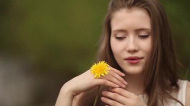 Bir kadın elinde sarı karahindiba ile oynuyor.