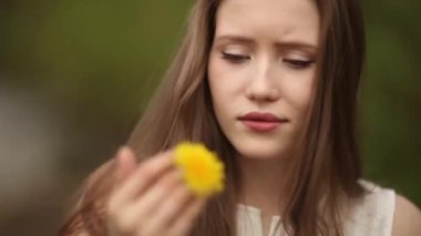 Bir kadın elinde sarı karahindiba ile oynuyor. Bahar geldi. Çiçek açan doğa.