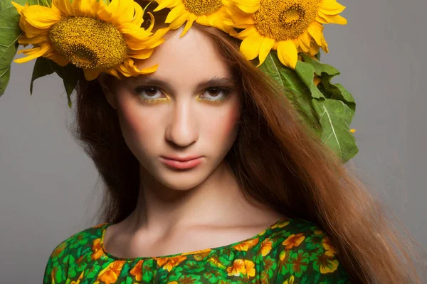 Vrouw met stijlvolle make-up en zonnebloemen rond haar hoofd — Stockfoto