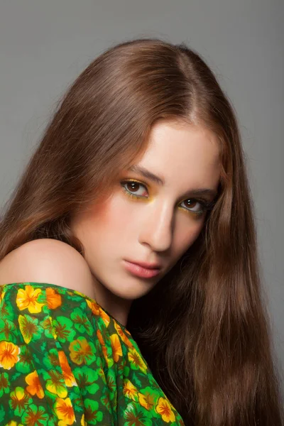 Vacker kvinna med snygg grön gul makeup i klänning med blommigt mönster — Stockfoto
