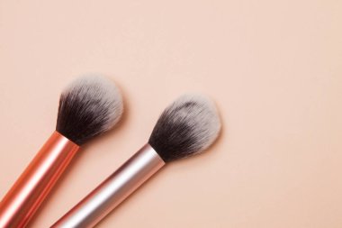 Pembe arka planda çeşitli kozmetik fırçalar. Profesyonel makyaj önleyici pudrası. Cilt bakımı için makyaj fırçaları ayarlandı.