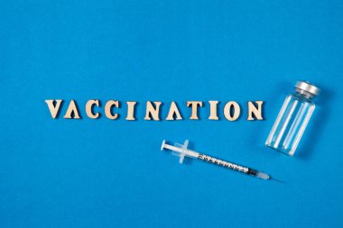 Aşı şişeleri ve şırınga enjeksiyon ilaçları mavi arka planda boş alanla.