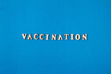 Mavi arka planda tahta harflerle kelime aşısı. Düz dizayn.