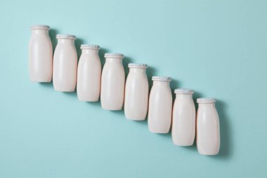 Probiyotik ve prebiyotik süt ürünleri içeren şişeler açık mavi arka planda. Kullanışlı mikroorganizmalı biyo-yoğurt. Biyolojik olarak aktif katkı maddeleri üretimi. Fermantasyon ve diyet sağlıklı yiyecekler.
