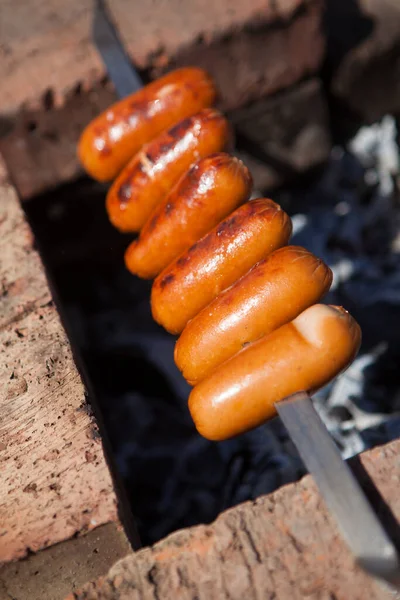 串に刺さったソーセージは 晴れた夏の日に炭火で揚げられます バーベキューでソーセージを焼き — ストック写真