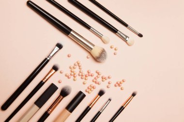 Pembe arka planda çeşitli kozmetik fırçalar. Profesyonel makyaj önleyici pudra göz farı fırçaları. Cilt bakımı için makyaj fırçaları ayarlandı.