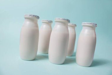 Probiyotik ve prebiyotik süt ürünleri içeren şişeler açık mavi arka planda. Kullanışlı mikroorganizmalı biyo-yoğurt. Biyolojik olarak aktif katkı maddeleri üretimi. Fermantasyon ve diyet sağlıklı yiyecekler.