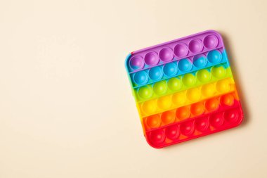 Gökkuşağı silikon duyusal antidepresan oyuncağı açık kahverengi arka planda. Üst görünüm.