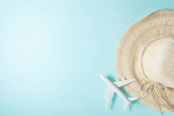 Traveling by plane. Layout on a blue background. Summer 2021 vacation and travel background with sun hat, plane. Flat lay.