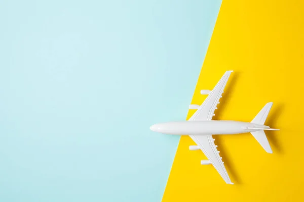 Flat lay design of travel concept with plane on yellow blue background with place for text.