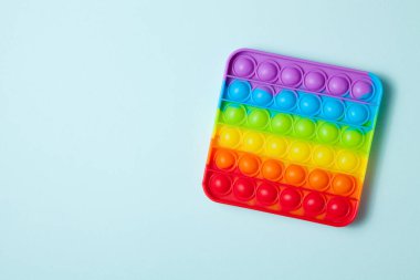 Gökkuşağı silikon duyusal antidepresan açık mavi arka planda oyuncak. Üst Manzara. Metin için boşluk.
