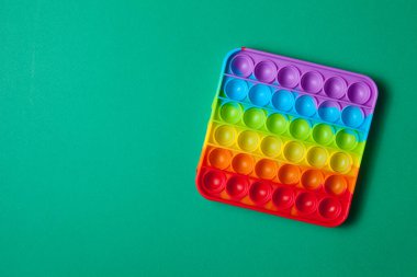 Gökkuşağı silikon duyusal antidepresan yeşil arka planda oyuncak. Üst Manzara. Metin için boşluk.