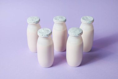 Probiyotik ve prebiyotik süt ürünleri içeren şişeler açık mor arka planda. Kullanışlı mikroorganizmalı biyo-yoğurt. Biyolojik olarak aktif katkı maddeleri üretimi. Fermantasyon ve diyet sağlıklı yiyecekler.