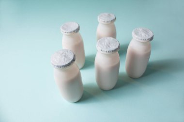 Probiyotik ve prebiyotik süt ürünleri içeren şişeler açık mavi arka planda. Kullanışlı mikroorganizmalı biyo-yoğurt. Biyolojik olarak aktif katkı maddeleri üretimi. Fermantasyon ve diyet sağlıklı yiyecekler.