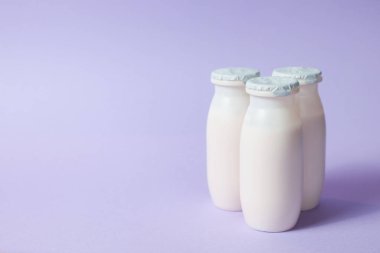 Probiyotik ve prebiyotik süt ürünleri içeren şişeler açık mor arka planda. Kullanışlı mikroorganizmalı biyo-yoğurt. Biyolojik olarak aktif katkı maddeleri üretimi. Fermantasyon ve diyet sağlıklı yiyecekler.